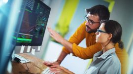 Closeup side view of couple of mid 20's software developers resolving some issues with the code they're currently working on.

NOTE: code lines on the screen are imaginary and blurred.