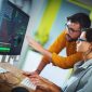 Closeup side view of couple of mid 20's software developers resolving some issues with the code they're currently working on.

NOTE: code lines on the screen are imaginary and blurred.
