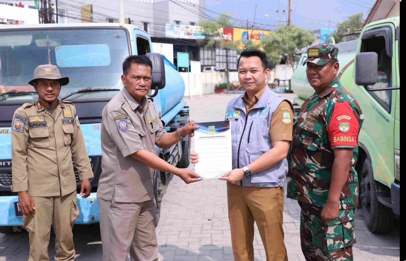 epala Bidang Informasi dan Komunikasi Publik (IKP) Diskominfosantik Kabupaten Bekasi, Rhamdan Nurul Ikhsan, secara simbolis menyerahkan bantuan 10.000 liter air bersih untuk warga Desa Hurip Jaya, di Halaman Kantor Kecamatan Babelan, pada Selasa, (24/09/2024). 