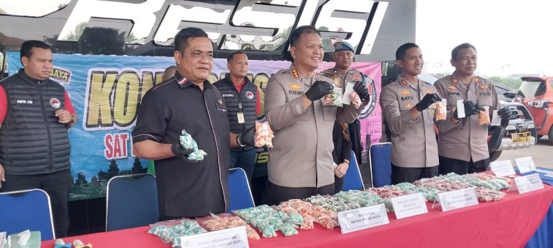 Kapolres Metro Bekasi Kota, Kombes Pol Kusumo Wahyu Bintoro (tengah), bersama jajaran menunjukkan barang bukti ribuan butir ekstasi yang berhasil disita dari tangan tersangka LS dalam pengungkapan kasus narkotika senilai Rp10 miliar. Barang bukti diamankan dari tiga lokasi berbeda: Jakarta Timur, Bogor, dan Depok. (Foto: Dok. Humas Polres Metro Bekasi Kota).