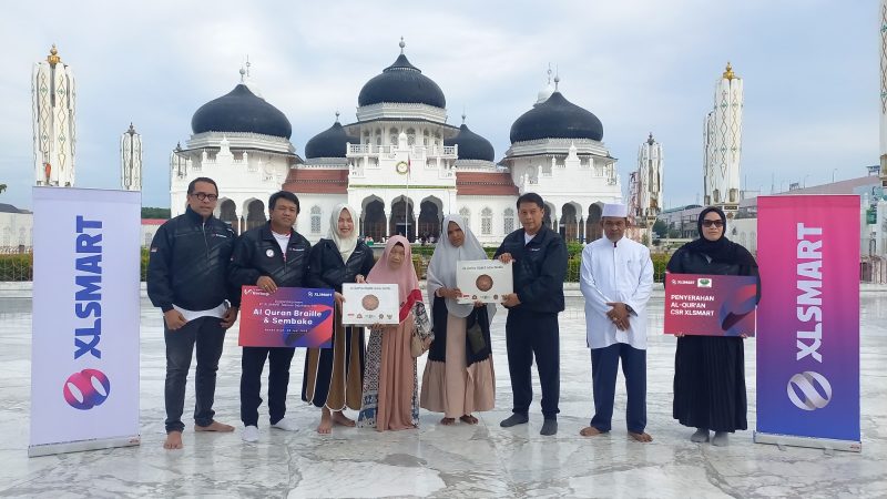 Tim XLSMART bersama perwakilan penerima manfaat berfoto usai menyerahkan Wakaf Al-Quran Braille dan paket sembako di halaman Masjid Raya Baiturrahman, Banda Aceh, Jumat (20/6/2025). 