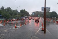 Situasi lalu lintas di sekitar akses menuju GT Cibubur pada Sabtu (5/7), saat hujan deras mengguyur kawasan tersebut. Meskipun terjadi genangan, arus kendaraan tetap terkendali berkat pengaturan petugas dan pengalihan jalur sementara.
