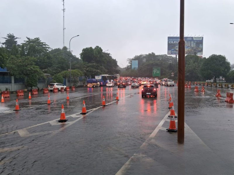 Situasi lalu lintas di sekitar akses menuju GT Cibubur pada Sabtu (5/7), saat hujan deras mengguyur kawasan tersebut. Meskipun terjadi genangan, arus kendaraan tetap terkendali berkat pengaturan petugas dan pengalihan jalur sementara.