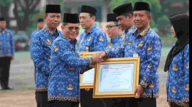 Asisten Administrasi Umum (Asda III) Sekretariat Daerah Kabupaten Bekasi, Jaoharul Alam (kiri depan), menyerahkan piagam penghargaan dari Kementerian PAN-RB kepada perwakilan perangkat daerah yang meraih predikat tinggi dalam pelayanan publik, dalam upacara peringatan Hari Koperasi Nasional ke-78 dan Upacara Korpri di Plaza Pemkab Bekasi, Cikarang Pusat, Kamis (17/07/2025). Pemerintah Kabupaten Bekasi meraih penghargaan nasional di bidang pelayanan publik untuk RSUD, Disdukcapil, dan Dinas Sosial.

