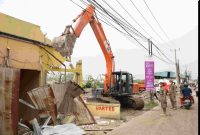 Petugas Satpol PP Kabupaten Bekasi bersama alat berat menertibkan bangunan liar yang berdiri di atas saluran irigasi di wilayah Kecamatan Babelan, Rabu (9/7/2025). Penertiban dilakukan sebagai bagian dari program normalisasi dan revitalisasi tanggul untuk mengantisipasi banjir.