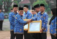 Asisten Administrasi Umum (Asda III) Sekretariat Daerah Kabupaten Bekasi, Jaoharul Alam (berkacamata, kiri depan), menyerahkan piagam penghargaan pelayanan publik dari Kementerian PAN-RB kepada perwakilan perangkat daerah dalam upacara peringatan Hari Koperasi Nasional ke-78 dan Upacara Korpri di Plaza Pemkab Bekasi, Cikarang Pusat, Kamis (17/07/2025).

