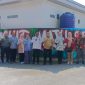 Foto sekelompok orang terdiri dari tim penilai, aparat, dan warga berdiri berjejer di depan mural warna-warni bertuliskan 