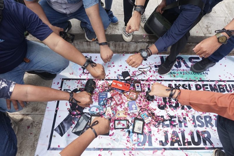 Sejumlah jurnalis yang tergabung dalam JMSI Batang–Pekalongan menggelar aksi solidaritas dengan mengenakan pita hitam di tangan, menaburkan bunga, serta meletakkan kartu identitas pers di atas poster sebagai bentuk duka dan protes atas pembunuhan jurnalis Al Jazeera