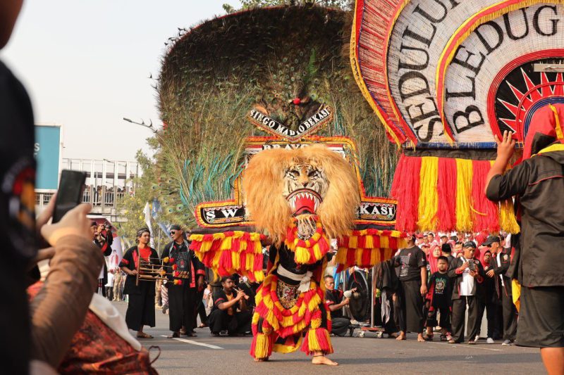 Foto Istimewa: Penampil seni Reog Ponorogo membawa topeng raksasa dengan hiasan bulu merak dalam salah satu atraksi budaya, menarik perhatian warga yang memadati area festival Pesona Nusantara Bekasi Keren.