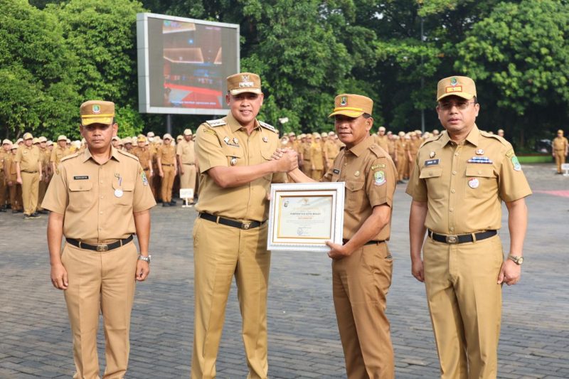 Wali Kota Bekasi menyerahkan piagam penghargaan kepada perwakilan perangkat daerah pada apel perdana Pemerintah Kota Bekasi tahun 2026, Senin (5/1/2026), sebagai bentuk apresiasi atas capaian kinerja, keterbukaan informasi publik, serta komitmen peningkatan pelayanan dan transformasi digital di lingkungan Pemkot Bekasi.