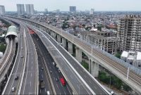 Tampak ruas jalan tol perkotaan yang terintegrasi dengan jalur transportasi massal (LRT) melintasi kawasan permukiman padat dan pusat pembangunan di wilayah Jabodetabek, mencerminkan pengembangan infrastruktur transportasi untuk meningkatkan konektivitas dan mengurai kemacetan perkotaan.