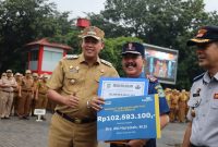 Wali Kota Bekasi Tri Adhianto menyerahkan secara simbolis manfaat Tabungan Hari Tua (THT) dan Pensiun Taspen kepada Drs. Abi Hurairah, M.Si, pada Apel Senin Pagi di lingkungan Kantor Pemerintah Kota Bekasi, Senin (26/1/2026), sebagai bentuk apresiasi atas pengabdian dan dedikasi aparatur yang memasuki masa purna bhakti.