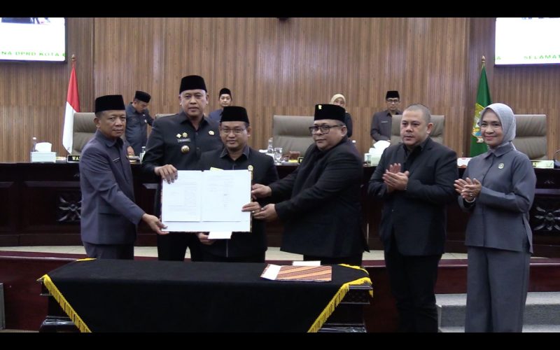Pimpinan DPRD Kota Bekasi bersama Wali Kota Bekasi Tri Adhianto dan jajaran Pemerintah Kota Bekasi menunjukkan dokumen Rancangan Kesepakatan usai penandatanganan persetujuan Raperda menjadi Perda tentang Inovasi Daerah dalam Rapat Paripurna Pembukaan Masa Sidang Tahun Anggaran 2026 di Gedung DPRD Kota Bekasi, Rabu (18/02/2026).