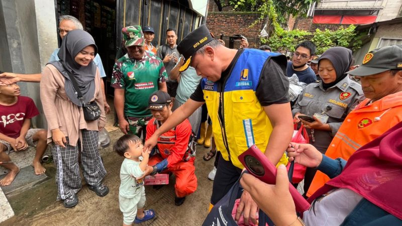 Wali Kota Bekasi Tri Adhianto berinteraksi dengan anak warga saat meninjau lokasi banjir di Gang Mawar, Kelurahan Margahayu, Kecamatan Bekasi Timur, Jumat (30/1/2026).
