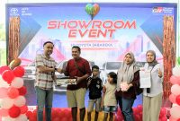 Suasana penuh kehangatan dalam Showroom Event JD Toyota Jababeka, di mana salah satu konsumen bersama keluarga menerima hadiah dan dokumen serah terima kendaraan, disaksikan tim sales Toyota sebagai bentuk apresiasi atas kepercayaan pelanggan.