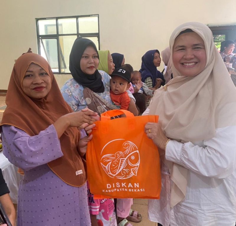 Petugas Dinas Perikanan Kabupaten Bekasi membagikan ikan kepada warga dalam program peningkatan konsumsi ikan untuk pencegahan stunting.