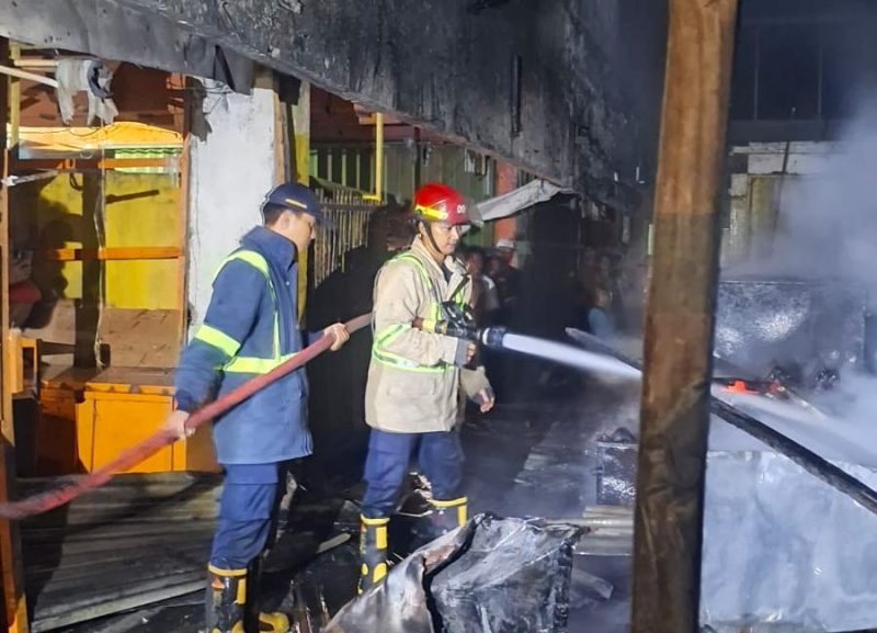 Petugas Dinas Pemadam Kebakaran Kabupaten Bekasi berupaya memadamkan kobaran api yang melanda Gedung Pasar Ramayana pada Minggu malam (17/5/2026). Kebakaran diduga dipicu korsleting listrik dan menghanguskan sedikitnya tujuh lapak pedagang.