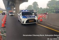 Petugas Kepolisian melakukan pengaturan lalu lintas saat penerapan contraflow di Ruas Tol Jakarta–Cikampek arah Cikampek, tepatnya di wilayah Cikarang Barat, Kabupaten Bekasi, Selasa (30/6/2026). Rekayasa lalu lintas diberlakukan dari KM 23 hingga KM 28 untuk mengurai kepadatan kendaraan.