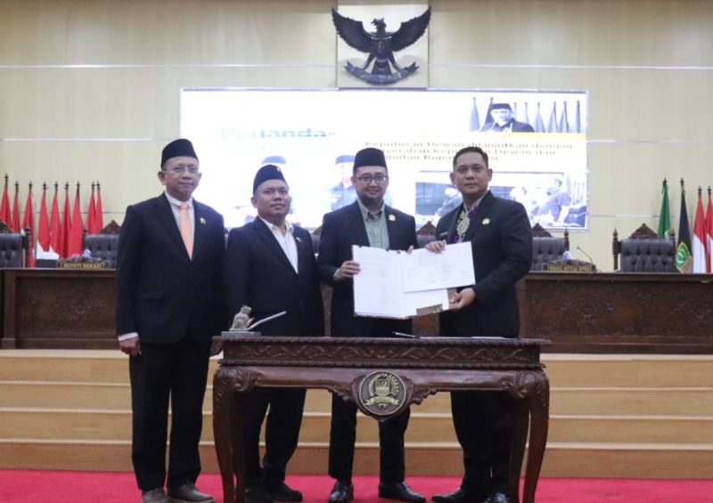 Keterangan Foto: Plt Bupati Bekasi H. Asep Surya Atmaja menandatangani persetujuan dua Raperda strategis menjadi Perda dalam Rapat Paripurna DPRD Kabupaten Bekasi di Cikarang Pusat, Kamis (12/06/2026).