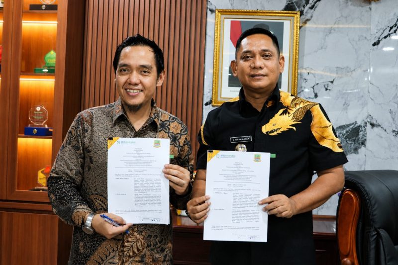 Plt Bupati Bekasi, dr. Asep Surya Atmaja (kanan), bersama Kepala BPJS Kesehatan Cabang Cikarang, Erwin Fadillah, menunjukkan dokumen addendum kerja sama Program Jaminan Kesehatan Nasional (JKN) usai penandatanganan di Kompleks Pemkab Bekasi, Rabu (1/7/2026).