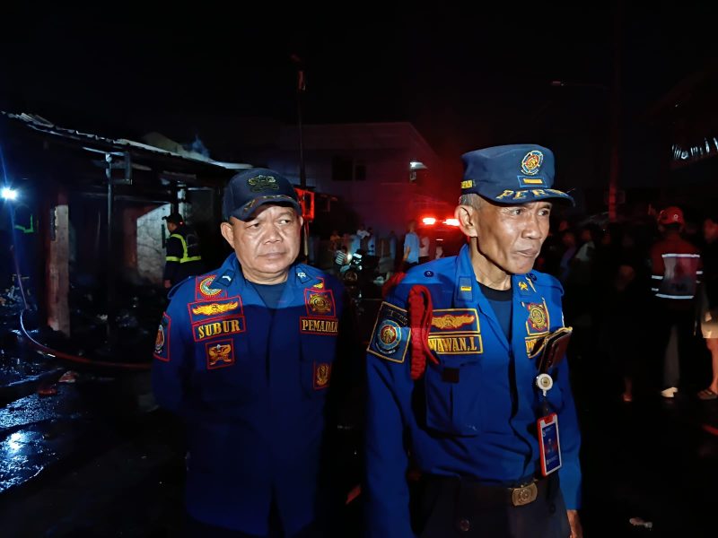 Komandan Pleton (Danton) Damkar Kabupaten Bekasi, Wawan (kanan), didampingi petugas Damkar Subur (kiri), memberikan keterangan kepada awak media usai memimpin proses pemadaman kebakaran empat kios di Pasar Tambun Selatan, Kabupaten Bekasi, Selasa (14/7/2026) malam. Kebakaran berhasil dipadamkan dalam waktu sekitar 20 menit tanpa menimbulkan korban jiwa.