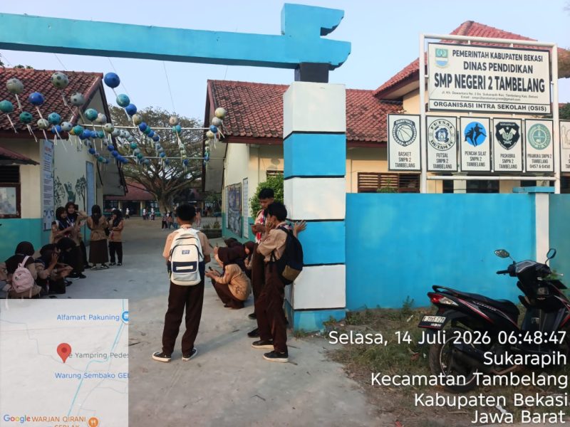 Suasana di pintu masuk SMP Negeri 2 Tambelang, Kecamatan Tambelang, Kabupaten Bekasi, Selasa (14/7/2026). Sejumlah wali murid menyoroti kondisi sarana dan prasarana sekolah yang dinilai masih memerlukan perhatian, di antaranya halaman sekolah yang masih berupa tanah serta sebagian pagar yang disebut belum memadai.