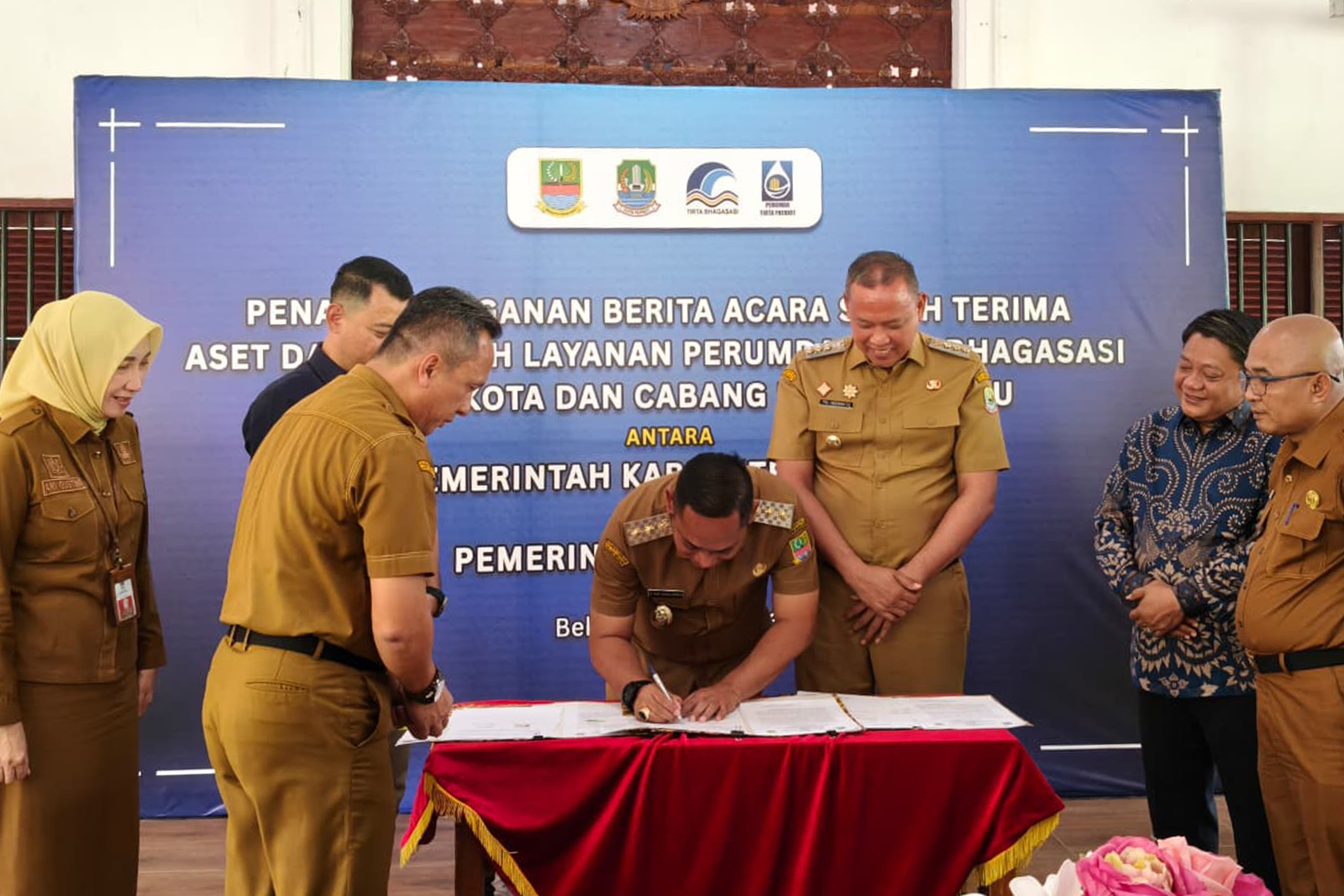 Wali Kota Bekasi Tri Adhianto bersama Plt Bupati Bekasi dr. Asep Surya Atmaja menandatangani berita acara serah terima aset dan wilayah layanan Perumda Tirta Bhagasasi Cabang Poncol dan Pondok Ungu kepada Perumda Tirta Patriot di Pendopo Wali Kota Bekasi, Senin (20/7/2026).