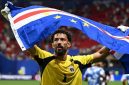 Kiper Tanjung Verde, Vozinha, mengangkat bendera negaranya usai pertandingan melawan Argentina pada babak 32 besar Piala Dunia 2026 di Miami. Meski kalah dramatis 2-3, penampilan heroik Blue Sharks sukses mencuri perhatian dunia sepak bola. (Foto: BBC/Getty Images)