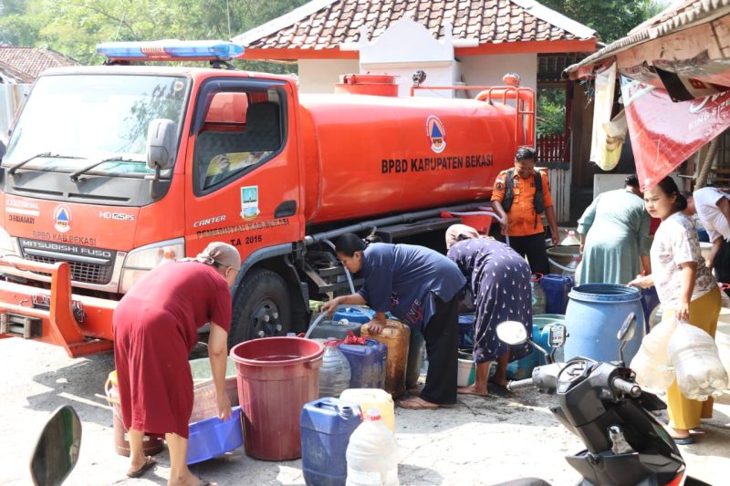 Warga Kampung Cihanjuang, Desa Ridogalih, Kecamatan Cibarusah, mengantre mengisi jeriken dan penampung air dari mobil tangki BPBD Kabupaten Bekasi. Sebanyak 10 ribu liter air bersih disalurkan untuk membantu ratusan keluarga yang terdampak kekeringan selama musim kemarau. Foto: Humas Pemkab Bekasi.