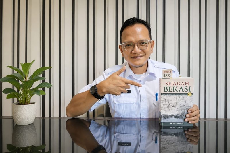 Penulis sekaligus sejarawan Bekasi, Endra Kusnawan, menunjukkan buku Sejarah Bekasi: Sejak Peradaban Buni Ampe Wayah Gini edisi ketiga yang kini menjadi salah satu koleksi unggulan Perpustakaan Daerah Kabupaten Bekasi. Buku setebal sekitar 600 halaman tersebut mengulas perjalanan sejarah Bekasi sejak Peradaban Buni hingga perkembangan pemerintahan modern. Foto: Istimewa