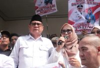 Haji Bahrudin, S.E. didampingi istri menyampaikan sambutan di hadapan ribuan pendukung usai resmi mendaftarkan diri sebagai bakal calon Kepala Desa Muktiwari periode 2026–2034 di Sekretariat Panitia Pilkades, Minggu (2/8/2026).