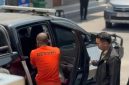 Petugas mengawal seorang warga negara Nigeria berinisial OCO yang mengenakan pakaian bertuliskan “DETENI” saat hendak dimasukkan ke dalam kendaraan. OCO ditetapkan sebagai tersangka dugaan tindak pidana keimigrasian setelah tercatat overstay selama 3.073 hari atau lebih dari delapan tahun.