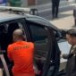 Petugas mengawal seorang warga negara Nigeria berinisial OCO yang mengenakan pakaian bertuliskan “DETENI” saat hendak dimasukkan ke dalam kendaraan. OCO ditetapkan sebagai tersangka dugaan tindak pidana keimigrasian setelah tercatat overstay selama 3.073 hari atau lebih dari delapan tahun.