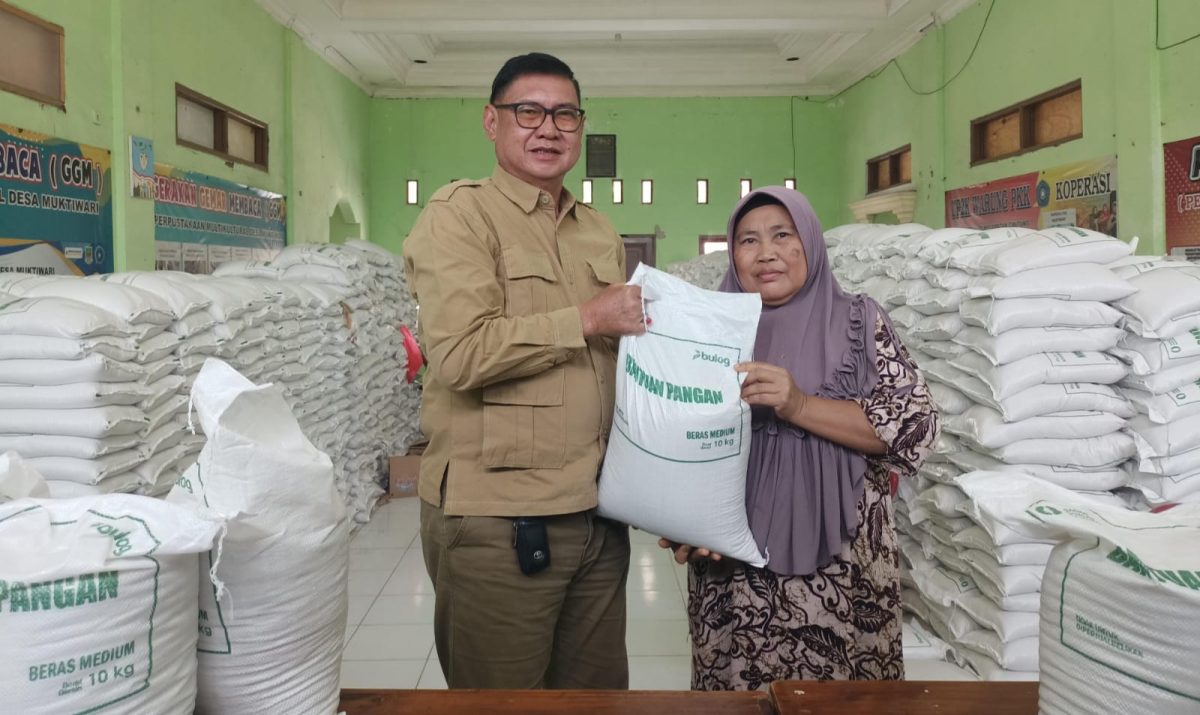 Kepala Desa Muktiwari, Bahrudin, SE, secara simbolis menyerahkan bantuan pangan berupa beras medium 10 kilogram kepada salah satu Keluarga Penerima Manfaat (KPM) di Aula Desa Muktiwari, Kecamatan Cibitung, Kabupaten Bekasi, Senin (24/8/2026). Sebanyak 1.902 KPM menerima bantuan 30 kilogram beras per KK melalui Program Bantuan Pangan Pemerintah Pusat yang disalurkan oleh Perum Bulog.