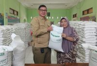 Kepala Desa Muktiwari, Bahrudin, SE, secara simbolis menyerahkan bantuan pangan berupa beras medium 10 kilogram kepada salah satu Keluarga Penerima Manfaat (KPM) di Aula Desa Muktiwari, Kecamatan Cibitung, Kabupaten Bekasi, Senin (24/8/2026). Sebanyak 1.902 KPM menerima bantuan 30 kilogram beras per KK melalui Program Bantuan Pangan Pemerintah Pusat yang disalurkan oleh Perum Bulog.