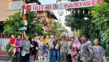Warga RT 02 RW 013, Kelurahan Jatimulya, Kecamatan Tambun Selatan, bersama Lurah Jatimulya Acep Abdi Eka Pradana berfoto bersama di depan gapura lingkungan usai mengikuti peninjauan Lomba Gang dalam rangka menyemarakkan HUT ke-81 Kemerdekaan RI dan Hari Jadi Kabupaten Bekasi ke-76, Minggu (16/8/2026).