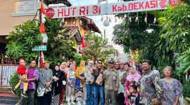 Warga RT 02 RW 013, Kelurahan Jatimulya, Kecamatan Tambun Selatan, bersama Lurah Jatimulya Acep Abdi Eka Pradana berfoto bersama di depan gapura lingkungan usai mengikuti peninjauan Lomba Gang dalam rangka menyemarakkan HUT ke-81 Kemerdekaan RI dan Hari Jadi Kabupaten Bekasi ke-76, Minggu (16/8/2026).