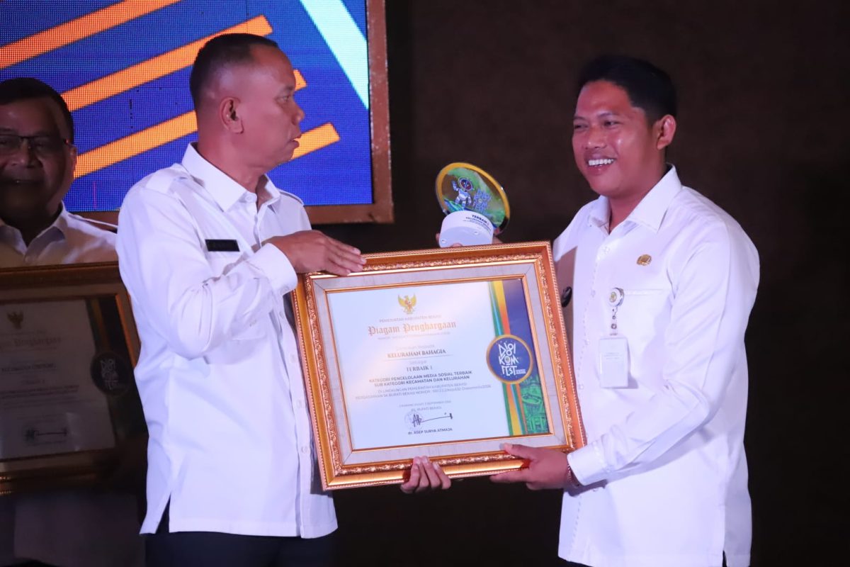 Lurah Bahagia, Khoirul Anwar (kanan), menerima penghargaan Juara 1 kategori Pengelolaan Media Sosial Terbaik Kelurahan dan Kecamatan dalam ajang Digital Komunikasi Festival (Digikomfest) 2026 yang digelar Diskominfosantik Kabupaten Bekasi di Aula KH. Noer Ali, Rabu (16/9/2026).