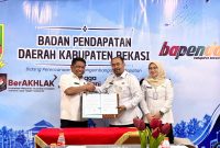 Kepala Bapenda Kabupaten Bekasi Iwan Ridwan bersama perwakilan Kantor Pertanahan Kabupaten Bekasi menunjukkan dokumen Perjanjian Kerja Sama (PKS) pertukaran dan pemanfaatan data pertanahan serta perpajakan daerah. Kerja sama tersebut menjadi langkah awal integrasi data NIB, NOP, dan ZNT untuk mendukung validasi data serta pengelolaan BPHTB di Kabupaten Bekasi.