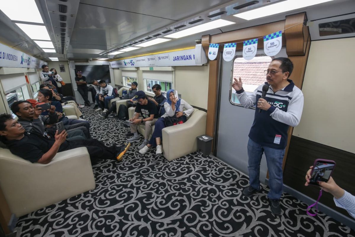 Karyawan XLSMART menjelaskan layanan jaringan 5G kepada peserta di dalam kereta dalam kegiatan pengenalan XL Ultra 5G+. Layanan ini menawarkan konektivitas berkecepatan tinggi untuk mendukung berbagai aktivitas digital masyarakat.