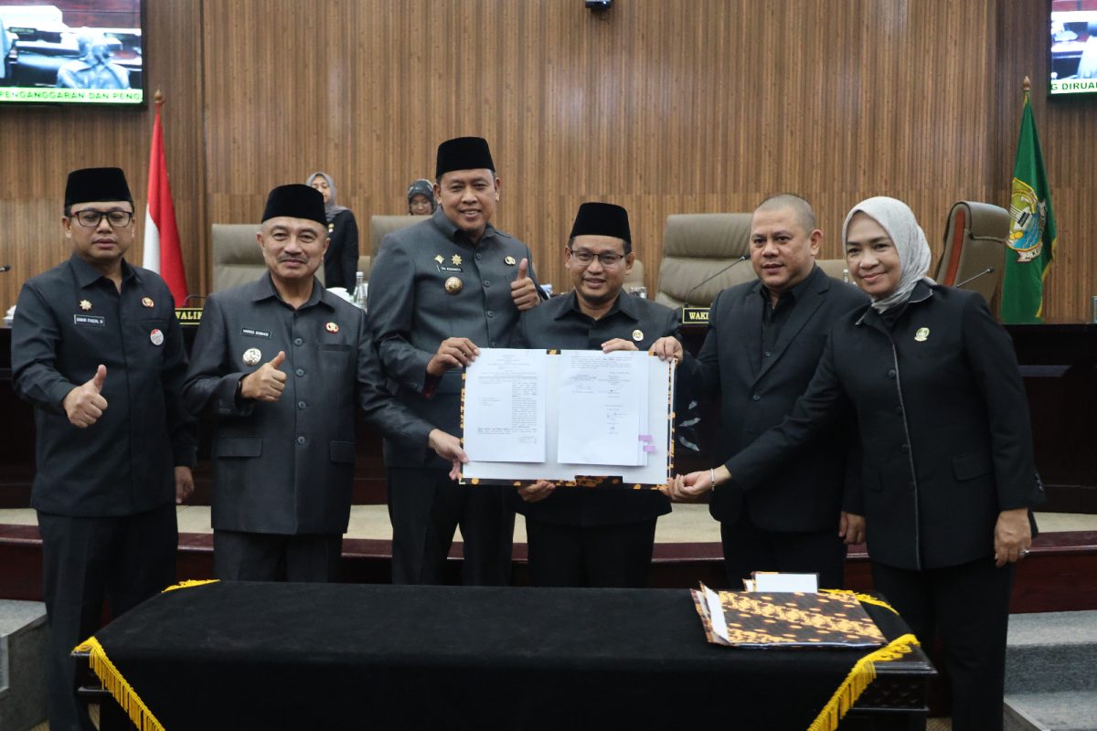 Wali Kota Bekasi Tri Adhianto bersama Wakil Wali Kota Bekasi Abdul Harris Bobihoe dan pimpinan DPRD Kota Bekasi menunjukkan dokumen kesepakatan RAPBD Tahun Anggaran 2027 dalam rapat paripurna di Gedung DPRD Kota Bekasi, Selasa (27/10/2026).