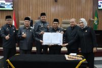 Wali Kota Bekasi Tri Adhianto bersama Wakil Wali Kota Bekasi Abdul Harris Bobihoe dan pimpinan DPRD Kota Bekasi menunjukkan dokumen kesepakatan RAPBD Tahun Anggaran 2027 dalam rapat paripurna di Gedung DPRD Kota Bekasi, Selasa (27/10/2026).