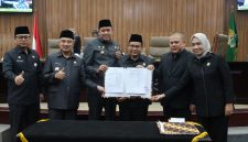 Wali Kota Bekasi Tri Adhianto bersama Wakil Wali Kota Bekasi Abdul Harris Bobihoe dan pimpinan DPRD Kota Bekasi menunjukkan dokumen kesepakatan RAPBD Tahun Anggaran 2027 dalam rapat paripurna di Gedung DPRD Kota Bekasi, Selasa (27/10/2026).