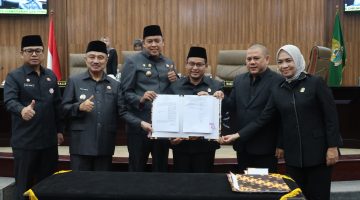 Wali Kota Bekasi Tri Adhianto bersama Wakil Wali Kota Bekasi Abdul Harris Bobihoe dan pimpinan DPRD Kota Bekasi menunjukkan dokumen kesepakatan RAPBD Tahun Anggaran 2027 dalam rapat paripurna di Gedung DPRD Kota Bekasi, Selasa (27/10/2026).