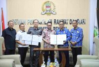 Plt Bupati Bekasi Asep Surya Atmaja bersama Ketua DPRD Kabupaten Bekasi Ade Sukron dan jajaran pemerintah daerah menunjukkan dokumen kesepakatan hasil evaluasi Gubernur Jawa Barat terhadap Perubahan APBD 2026 di Gedung DPRD Kabupaten Bekasi, Senin (19/10/2026).
